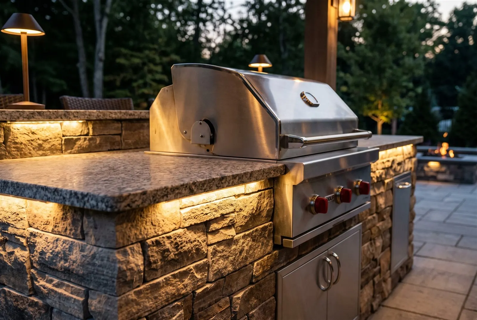 Nahdetail einer Steinarbeitsplatte mit Einbaugrill und warmer Beleuchtung in der Dämmerung