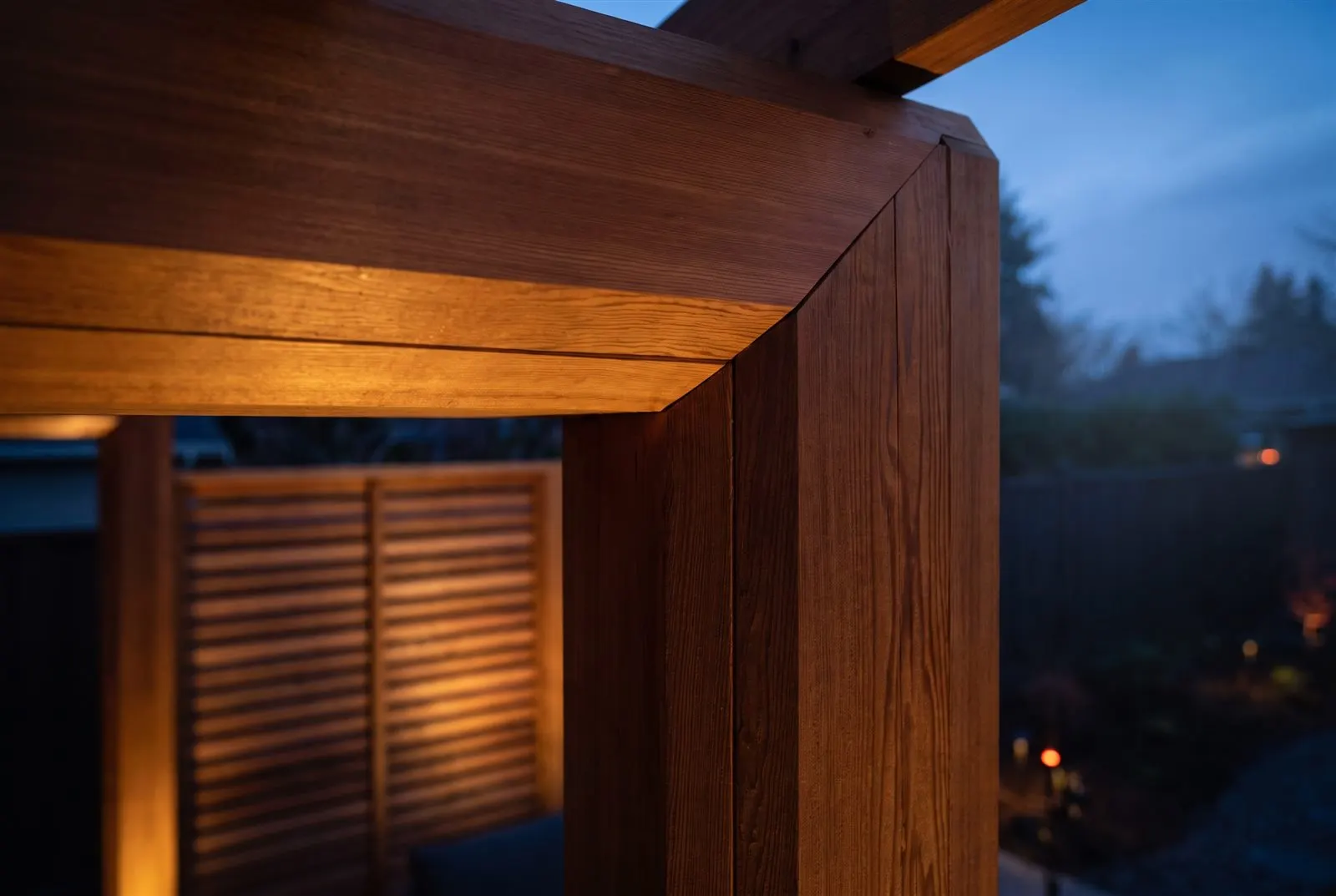 Close detail of cedar pergola joinery with warm wood grain and lighting at dusk